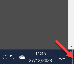 The right-hand end of the Windows taskbar with a red arrow pointing at the thin Show desktop strip beside the clock