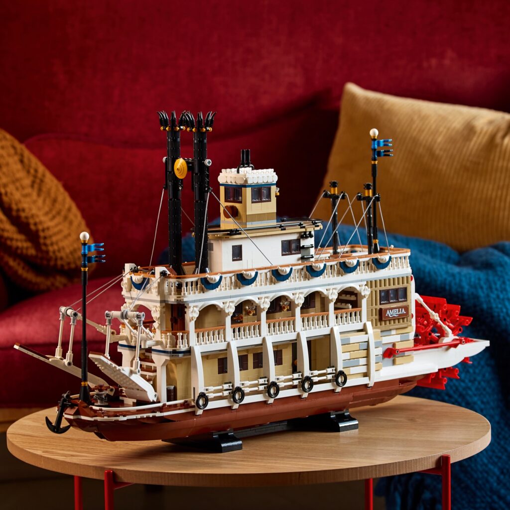 The LEGO River Steamboat, a white paddle steamer with a red paddle wheel and two tall black funnels, on a small wooden table