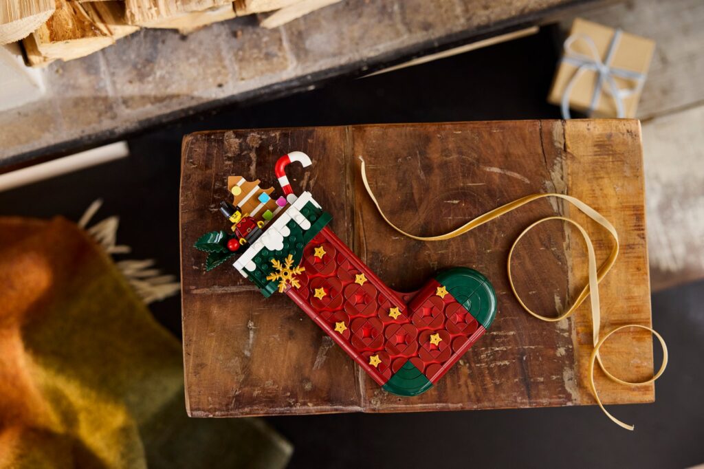 The LEGO Christmas Stocking, a red brick-built stocking with gold stars, holly and a candy cane, lying on a wooden board